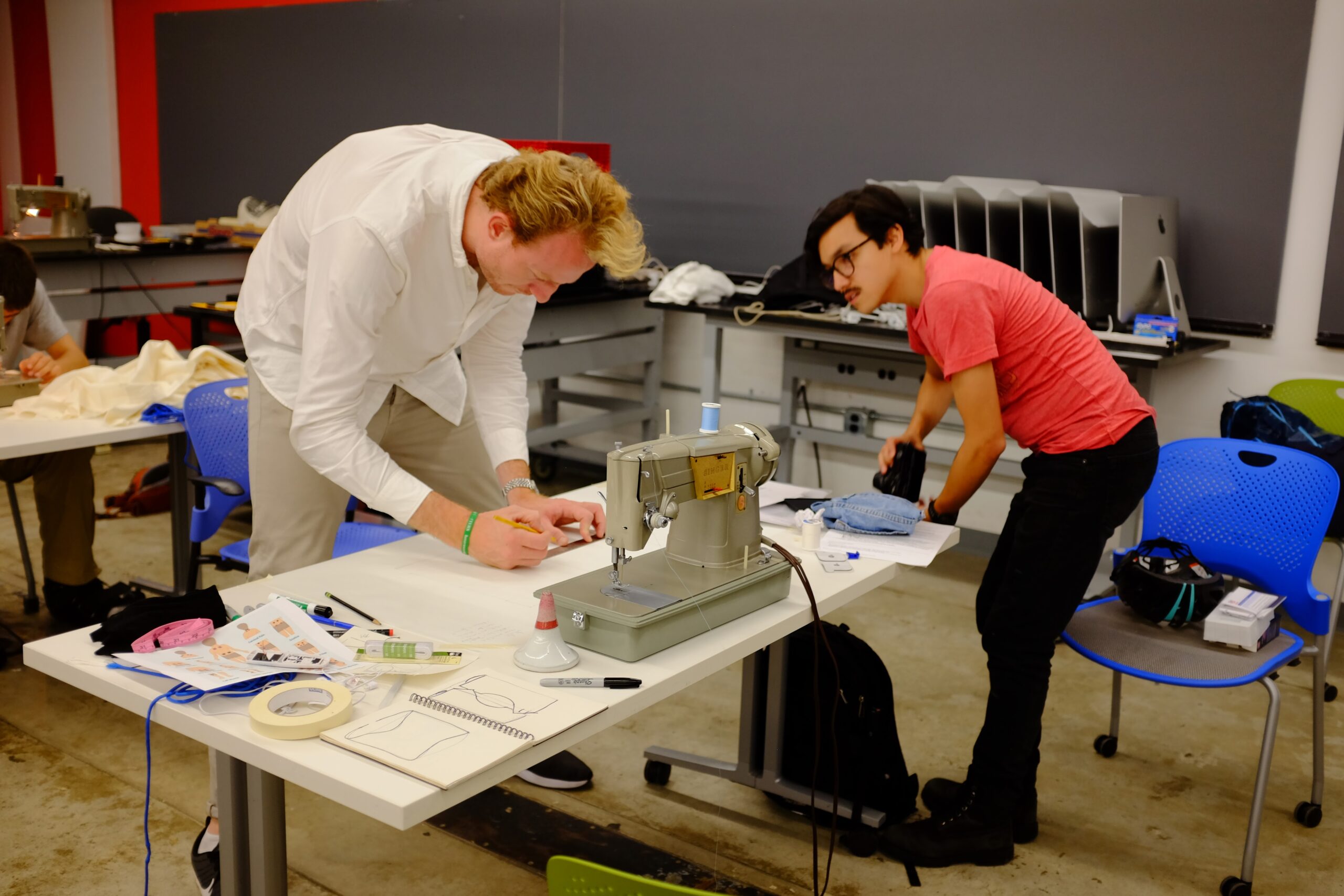 Two people crouched over a table with electronics on the surface of the table.